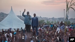 Opposition leader Kizza Besigye, center-left, gestures as he speaks to thousands of his supporters at an election rally at dusk on the outskirts of Kampala, Uganda Sunday, Feb. 14, 2016. 