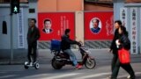 FILE PHOTO: People cross a street in front of posters depicting late Chairman Mao Zedong (R) and China's President Xi Jinping in Shanghai, China, March 1, 2016. 