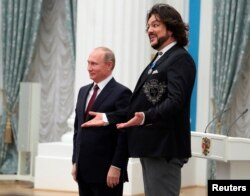 FILE - Pop singer Philipp Kirkorov reacts next to Russia's President Vladimir Putin after having been decorated with the Order of Honor during an awarding ceremony at the Kremlin in Moscow, Nov. 15, 2017.
