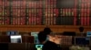 FILE - Traders are seen in front of a screen with mostly red trading figures, at Thailand's Stock Exchange, in Bangkok, March 13, 2020.