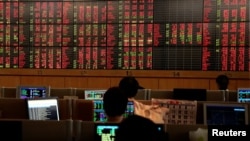 FILE - Traders are seen in front of a screen with mostly red trading figures, at Thailand's Stock Exchange, in Bangkok, March 13, 2020.