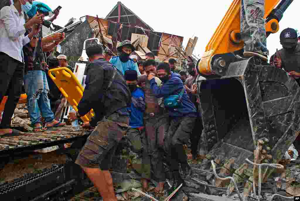 Rescuers assist a survivor pulled out from the ruin of a government building collapsed during an earthquake in Mamuju, West Sulawesi, Indonesia.