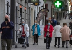 Para pejalan kaki mengenakan masker wajah di Madrid, Spanyol, 13 Mei 2020.