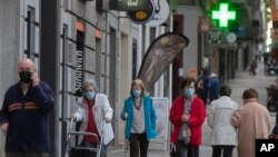 Des personnes portant des masques faciaux pour se protéger contre le coronavirus marchent dans les rues de Madrid, Espagne, le 13 mai 2020.