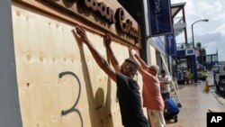 People board up an Urban Cottage store in preparation for Hurricane Humberto in Hamilton, Bermuda, Sept. 18, 2019.