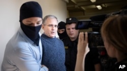 FILE - Paul Whelan, a former U.S. Marine, second left, who was arrested for alleged spying in Moscow at the end of 2018, speaks to a journalist as he escorted by Federal Security Service officers to a court room in Moscow, Russia, Aug. 23, 2019.