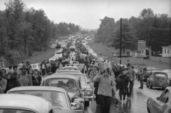 FILE - Hundreds of rock music fans jam a highway leading from Bethel, N.Y., as they try to leave the Woodstock Music and Art Festival, Aug. 16, 1969.