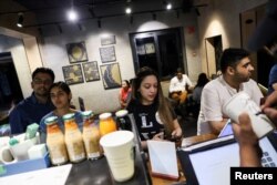 Customers stand next to a counter at a Starbucks' outlet at a market in New Delhi