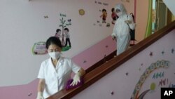 In this June 30, 2021, file photo, staff of the Pyongyang Primary School No. 4 clean stairwells in Pyongyang, North Korea. Pyongyang has not reported any COVID-19 cases since the pandemic began in late December 2019. 