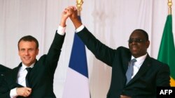 Le président sénégalais Macky Sall (à gauche) et le président français Emmanuel Macron (à droite) se tiennent la main après le discours de Macron à Saint-Louis, au Sénégal, le 3 février 2018.