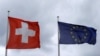 FILE - An EU flag flies beside Switzerland's national flag near the German-Swiss border in Rheinfelden, Germany, March 11, 2019. 