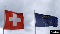 FILE - An EU flag flies beside Switzerland's national flag near the German-Swiss border in Rheinfelden, Germany, March 11, 2019. 