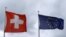 FILE - An EU flag flies beside Switzerland's national flag near the German-Swiss border in Rheinfelden, Germany, March 11, 2019. 