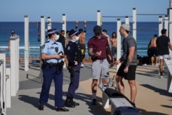 Patrolling police officers check IDs of people working out at a Bondi Beach outdoor gym area during a lockdown to curb the spread of COVID-19 outbreak in Sydney, Australia, July 27, 2021.