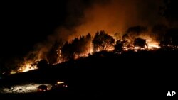 Firefighters watch from their fire trucks as wildfires continue to burn, Oct. 12, 2017, near Calistoga, Calif. 