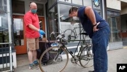 In this June 9, 2020 photo, Harvey Curtis, left, discusses repair plans with customer Jack Matheson outside Sidecountry Sports, a bike shop in Rockland, Maine.