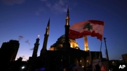 Anti-government protesters wave Lebanese flags and chant slogans during ongoing protests against the Lebanese government, in Beirut, Feb. 1, 2020.