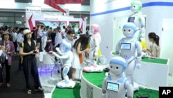 In this image taken from video, visitors look at iPal robots during the Shanghai CES electronic show in Shanghai, China, June 8, 2017. More than 50 companies are showcasing a new generation of robots at this week's Shanghai CES electronics show, most of which serve as companions at home, or butlers in shopping malls. 