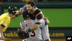 El pitcher Joaquín Benoit carga a Alex Ávila celebrando su triunfo en el quinto juego de los playoffs contra los Atléticos de Oakland.
