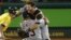 El pitcher Joaquín Benoit carga a Alex Ávila celebrando su triunfo en el quinto juego de los playoffs contra los Atléticos de Oakland.