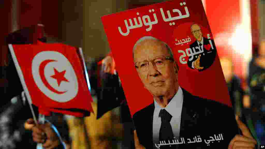 Un partisan tenant une affiche du candidat présidentiel tunisien Béji Caïd Essebsi, célèbre après les premiers résultats du second tour de l&#39;élection présidentielle en Tunisie, à Tunis, dimanche 21 décembre 2014.