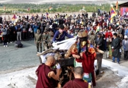 FILE - A relative places khadaks, a white piece of silk cloth, over the pyre of Nyima Tenzin, a senior Tibetan official from India's Special Frontier Force, during his cremation ceremony in Leh, Sept. 7, 2020.