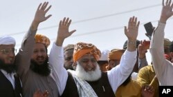 Maulana Fazlur Rehman, center, head of the Jamiat Ulema-e-Islam party, waves to supporters on his arrival to lead an anti-government march, in Karachi, Pakistan, Oct. 27, 2019.