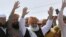 Maulana Fazlur Rehman, center, head of the Jamiat Ulema-e-Islam party, waves to supporters on his arrival to lead an anti-government march, in Karachi, Pakistan, Oct. 27, 2019.