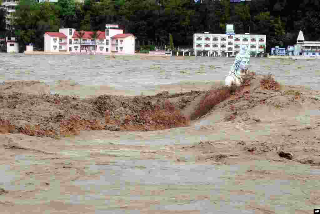 Arus sungai bergerak cepat menerpa sebuah patung Hindu selama hujan deras dan air pasang di kota Rishikesh, negara bagian Uttrakhand, India.