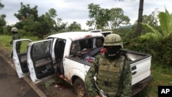 Soldiers stand guard next to a vehicle belonging to gunmen after a shootout in the municipality of Tacambaro near Morelia August 16, 2011.