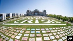 Activists of the Fridays for Future movement place protest posters for climate protection in front the German parliament building, the Reichstag, in Berlin, Germany, April 24, 2020. 