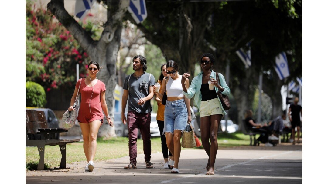 Pedestrians walk on a boulevard as Israel rescinds the mandatory wearing of face masks outdoors, in Tel Aviv, Apr. 18, 2021.