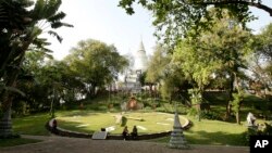 In this photo taken, Feb. 25, 2013, visitors sit near a large clock displayed on the ground at Wat Phnom, in Phnom Penh, Cambodia. (AP Photo/Heng Sinith)