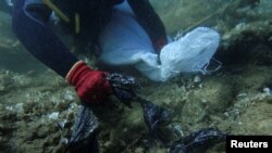 A volunteer diver of the environmental group Aegean Rebreath gathers plastic waste from the bottom of the sea, off the island of Andros, Greece, July 20, 2019. Picture taken July 20, 2019. (REUTERS/Stelios Misinas)