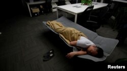 Ma Zhenguo, a system engineer at RenRen Credit Management Co., sleeps on a camp bed at the office after finishing work early morning, in Beijing, China, April 27, 2016. 