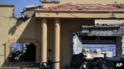 A Libyan NTC fighter walks amongst the rubble of a destroyed building the Gadhafi palace in Sirte, Oct. 9, 2011.