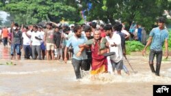 দক্ষিণ ভারতের অন্ধ্রপ্রদেশের নেলোরে বন্যার পানিতে প্লাবিত একটি রাস্তা দিয়ে মানুষ হেঁটে যাচ্ছে।(এপি ছবি)