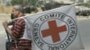 FILE - An International Red Cross worker stands with the organization's flag near Erez Crossing, northern Gaza Strip. The organization has established the Red Family Fund to honor humanitarian aid workers who have died in the line of duty. 