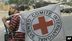 FILE - An International Red Cross worker stands with the organization's flag near Erez Crossing, northern Gaza Strip. The organization has established the Red Family Fund to honor humanitarian aid workers who have died in the line of duty. 