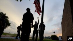 Port Arthur firefighters lower a U.S. flag at a post office at sunset as they wait for Hurricane Laura to make landfall, Aug. 26, 2020, in Port Arthur, Texas.