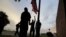 Port Arthur firefighters lower a U.S. flag at a post office at sunset as they wait for Hurricane Laura to make landfall, Aug. 26, 2020, in Port Arthur, Texas.