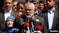 Hamas Chief Ismail Haniyeh gestures during a news conference as the wife of slain senior Hamas militant Mazen Fuqaha stands next to him, in Gaza City, May 11, 2017. 