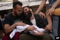 Palestinians mourn their relatives killed in the Israeli bombardment of the Gaza Strip, in a morgue in Khan Younis, Oct. 29, 2023.