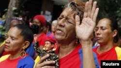 A woman holds a figurine of Venezuelan President Hugo Chavez, as she attends a mass to pray for Chavez's health in Caracas December 11, 2012.