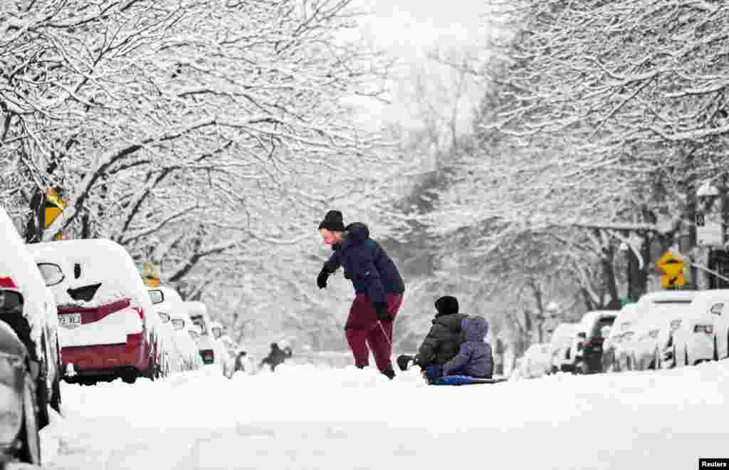 A man pulls children in a sled along a street after the first significant snowfall of the season in the Canadian city of Montreal on December 8, 2024. REUTERS/Graham Hughes