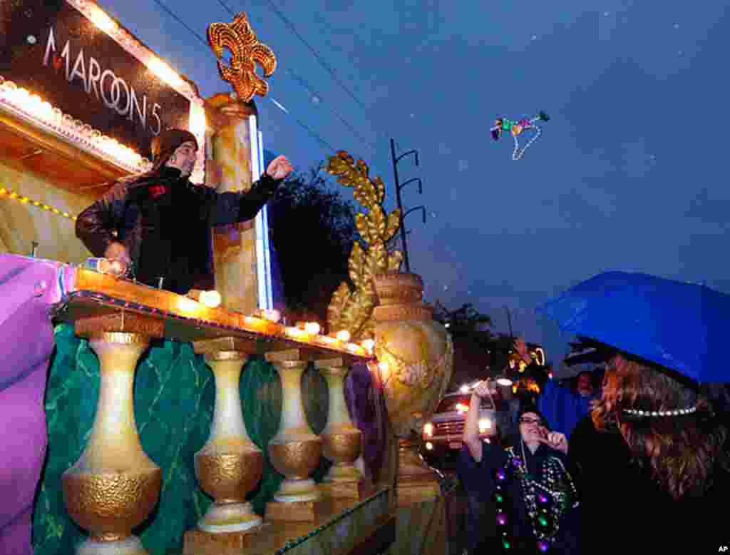A member of the band Maroon 5 throws beads to Mardi Gras revelers before the start of the Krewe of Endymion parade in New Orleans, February 20, 2012. (AP Photo)