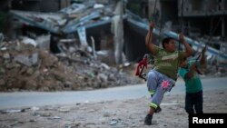 Anak-anak Palestina bermain di dekat reruntuhan bangunan di Beit Hanoun, Jalur Gaza yang hancur akibat serangan Israel tahun lalu (foto: dok).