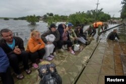 Ukrainian servicemen ferry locals through a flooded area after the Nova Kakhovka dam breached, in the flooded village of Afanasiivka