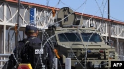 A U.S. Customs and Border Protection Office agent walks past a Border Patrol vehicle during an operative to find illegal migrants at the International Bridge Paso del Norte-Santa Fe in Ciudad Juarez, Mexico, July 1, 2019.