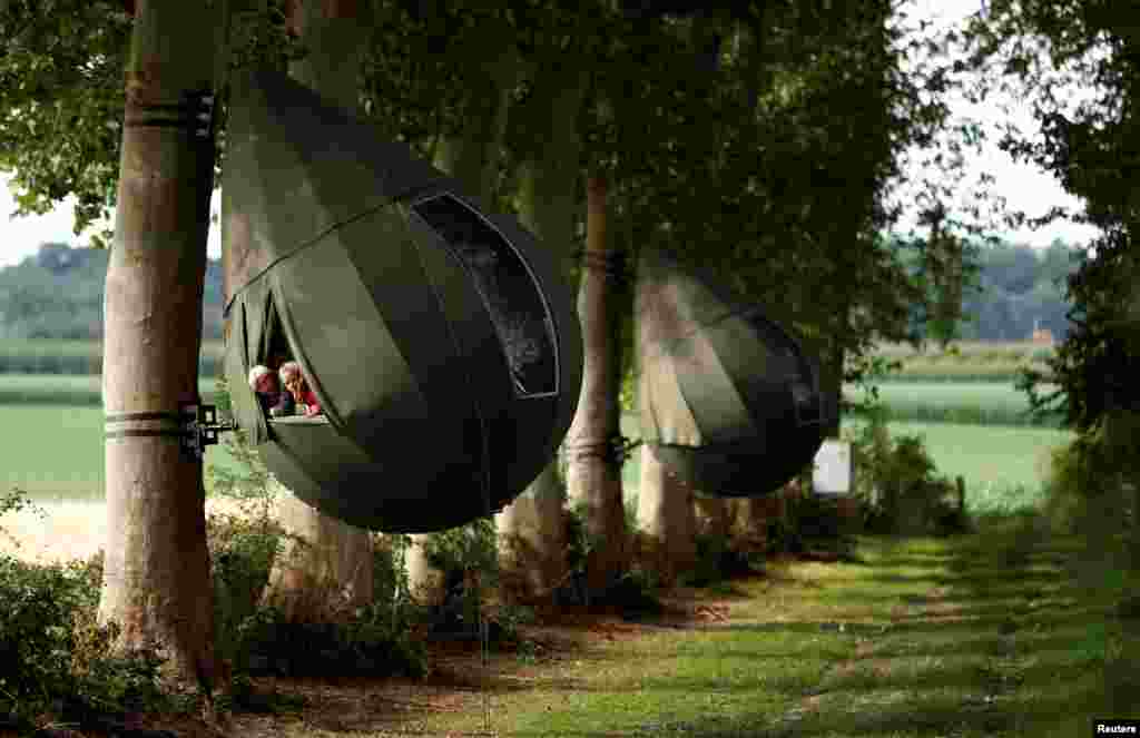 Guests sit inside a teardrop-shaped tent hanging from a tree created by Dutch artist Dre Wapenaar, offering an unusual accommodation for tourists in the Belgian countryside, near Borgloon, Belgium, July 7, 2020.